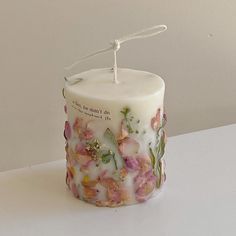 a white candle with pink flowers on it