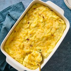 a casserole dish with cheese and other toppings on a blue table cloth