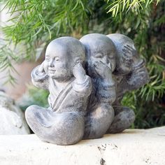 a statue of two people sitting on top of each other in front of a tree