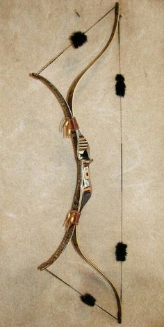 a bow that is on the ground with some black feathers around it and an arrow in the middle