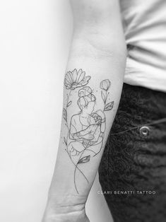 a black and white photo of a woman's arm with a flower tattoo on it