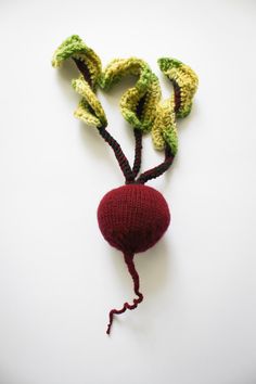 a crocheted radish with two leaves attached to it on a white surface