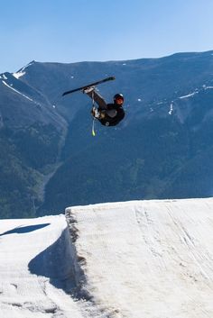 a man flying through the air while riding skis on top of a snow covered slope