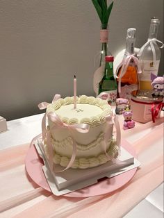 a birthday cake with two candles on it sitting on top of a pink table cloth