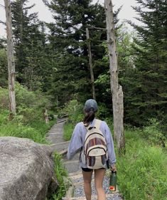 a woman walking up some steps in the woods with a backpack and water bottle on her back