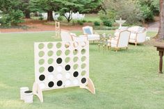 an outdoor game set up in the grass with chairs and tables around it on either side