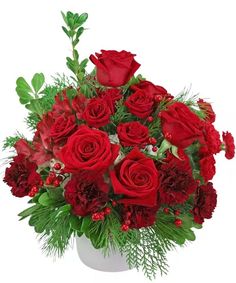 a white vase filled with red roses and greenery