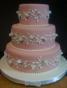 a pink wedding cake with white flowers and pearls