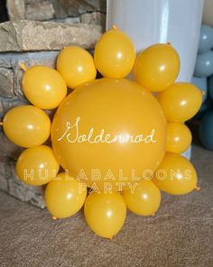 balloons in the shape of a sun with names on them are sitting next to a brick wall