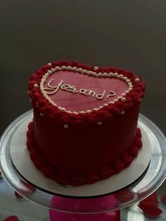 a heart shaped cake with the words yes and p on it sitting on a plate