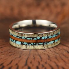 two bands with turquoise and brown inlays are on top of a wooden table