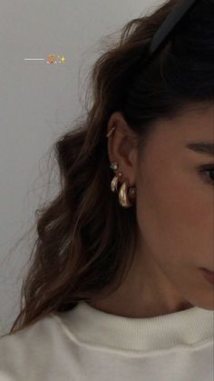 a close up of a person wearing earring's and a white sweater shirt