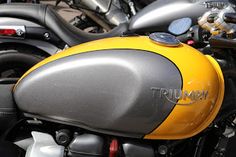 there are many motorcycles that are parked in the street side by side, one is yellow and gray