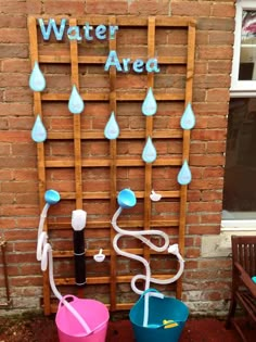 two buckets with water attached to them sitting in front of a brick wall next to a sign that says water area