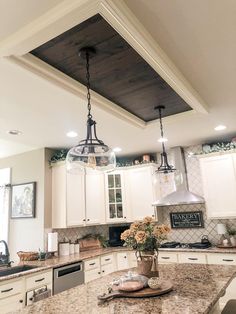 a kitchen with white cabinets and granite counter tops, two pendant lights over the island