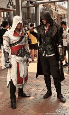 two men dressed in costumes standing next to each other on a brick floored walkway