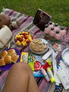 a woman laying on top of a blanket next to a picnic table filled with food