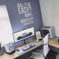 a desk with a computer and speakers on it in front of a wall that says, will it be easy? nope worth it absolutely