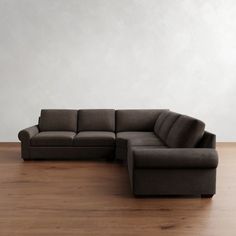 a couch sitting on top of a hard wood floor next to a white wall in an empty room