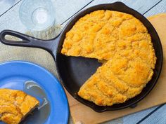 a skillet with some food in it on a blue plate next to a glass of water