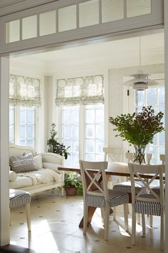 a living room with white furniture and windows