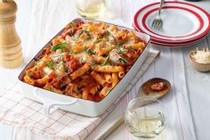 a white casserole dish filled with pasta and sauce on top of a table