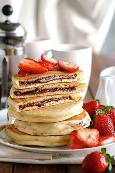 pancakes are stacked on top of each other with chocolate sauce and strawberries in the middle