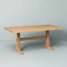 a wooden table sitting on top of a white floor next to a gray wall in an empty room