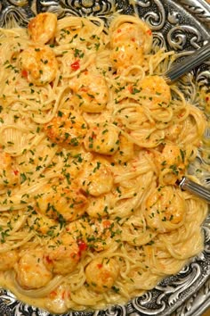 pasta with shrimp and parmesan cheese sauce in a silver bowl on a table