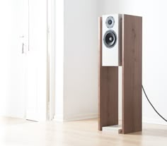 a speaker stands next to an open door in a white room with wood floors and walls