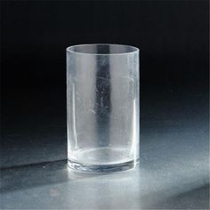 a clear glass sitting on top of a gray table next to a black wall and floor