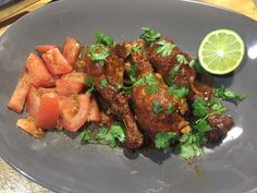 a plate topped with meat and veggies next to a lime