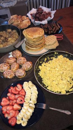 a table topped with plates of food and pans filled with different types of breakfast foods