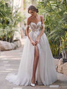 a woman in a white wedding dress posing for the camera with her legs crossed and wearing high heels