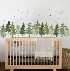 a baby's crib in front of a wall with trees painted on it