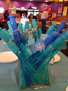 blue toothbrushes are in a clear vase on a table with white plates and napkins