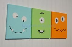 three canvases with faces painted on them are lined up in a row against a white wall