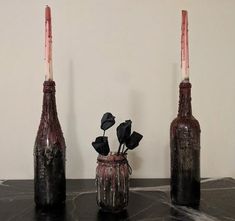 three vases with flowers in them sitting on a black counter top next to each other