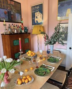 a dining room table with plates and oranges on it, candlesticks and flowers