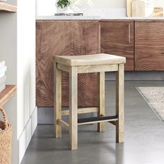 a wooden stool sitting in the middle of a kitchen