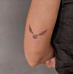 a small tattoo on the arm of a person with an owl and bird wing design