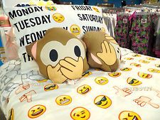 a monkey pillow sitting on top of a bed covered in emoticive smiley faces