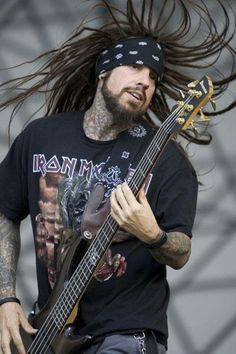 a man with long hair playing a bass guitar on stage at a music festival or concert