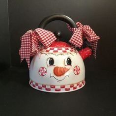 a red and white checkered tea kettle with a snowman face on it