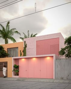 a pink building with two doors and some plants