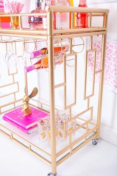 a gold bar cart with drinks and glasses on it's shelves in a bathroom