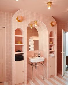 a bathroom with pink and white tiles on the walls, sink and shelving unit