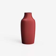 a red vase sitting on top of a white table