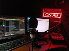 a desk with two computer monitors and a microphone in front of a red on air sign