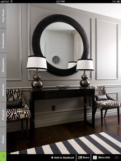 a black and white room with two lamps, a mirror and a table in front of it